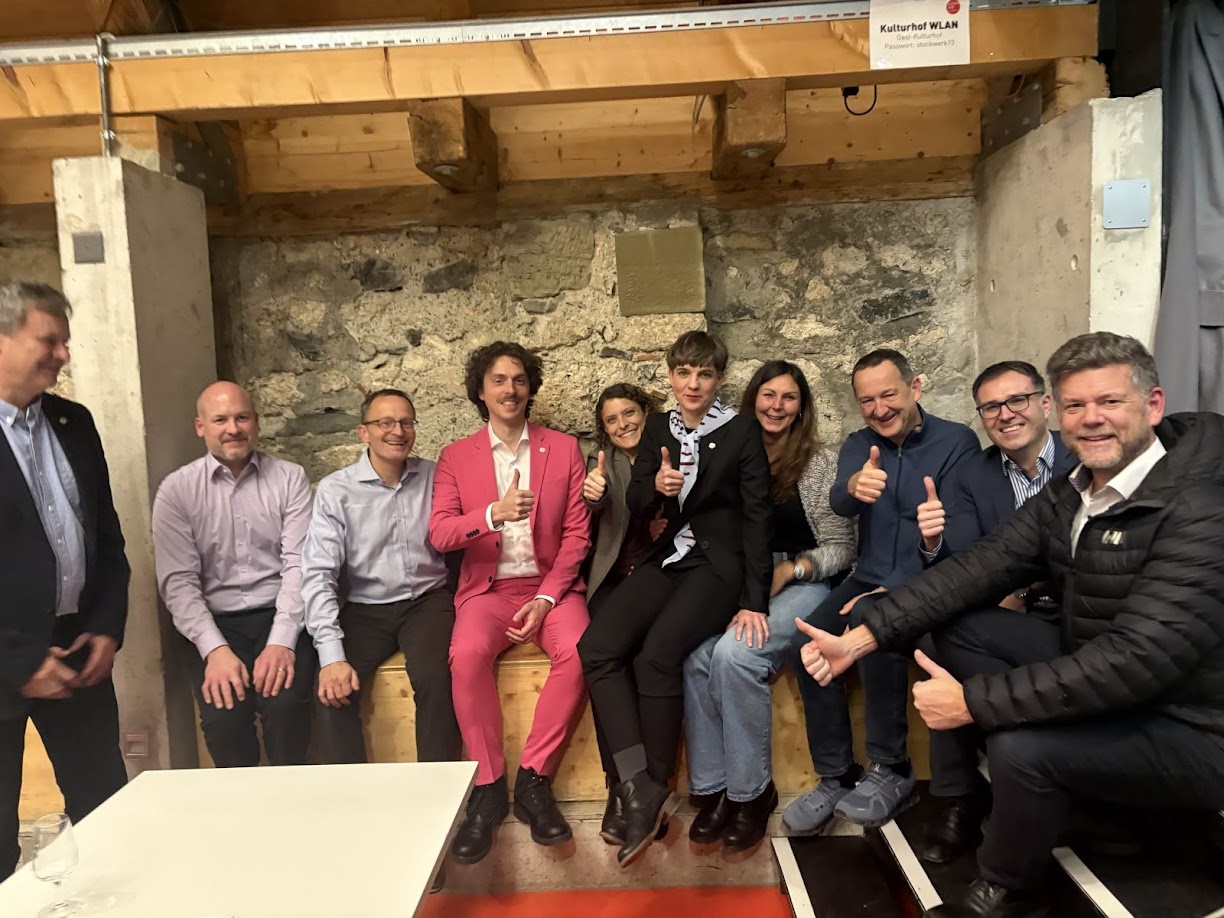 Die Mitglieder der EVP-GLP-Mitte-Fraktion sitzen eng aufeinander in einem Winkel der Schlos Köniz und halten den Daumen hoch. In der Mitte (in pink): Casimir von Arx.